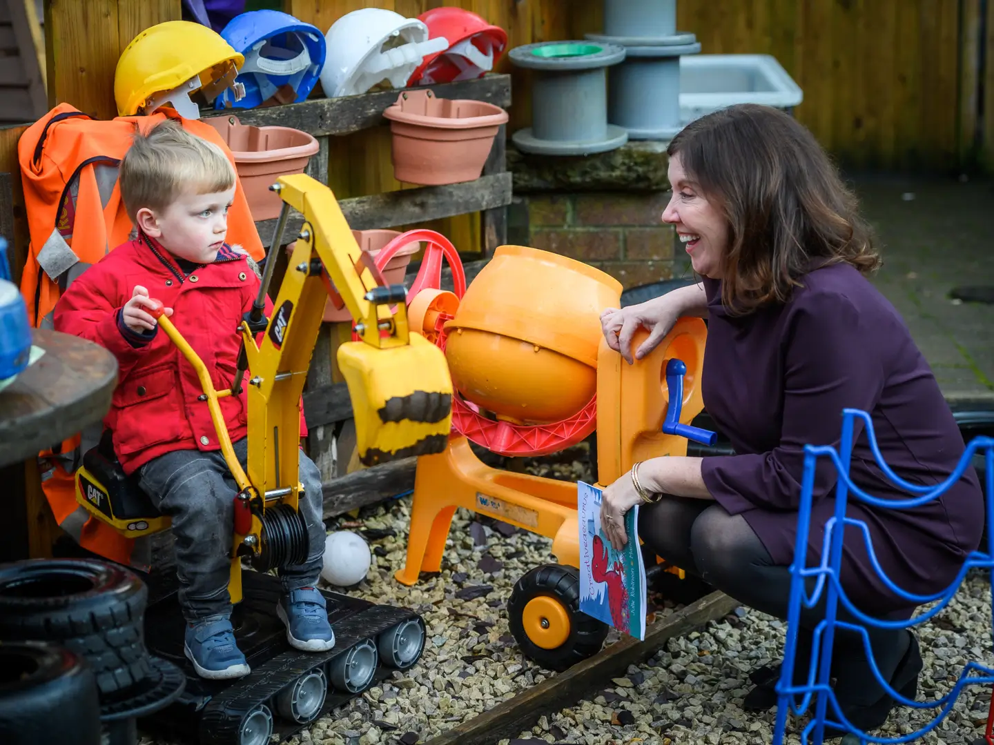 Dame Rachel de Souza laughing with toddler in out door play area