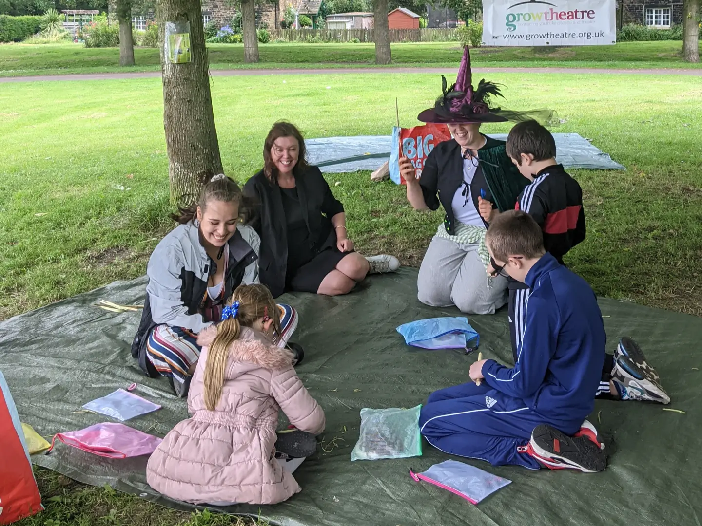 Dame Rachel de Souza sitting with children under a tree