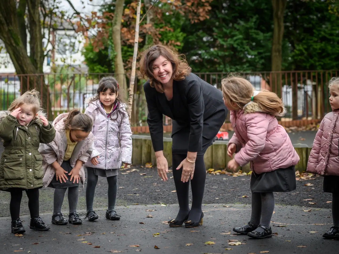 Dame Rachel de Souza playing in the playground with a group of your girls