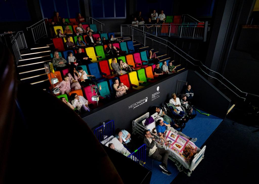 A full view of the seating in the MediCinema with children in hospital beds in the front section.