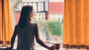 Thoughtful woman at home looking through the window