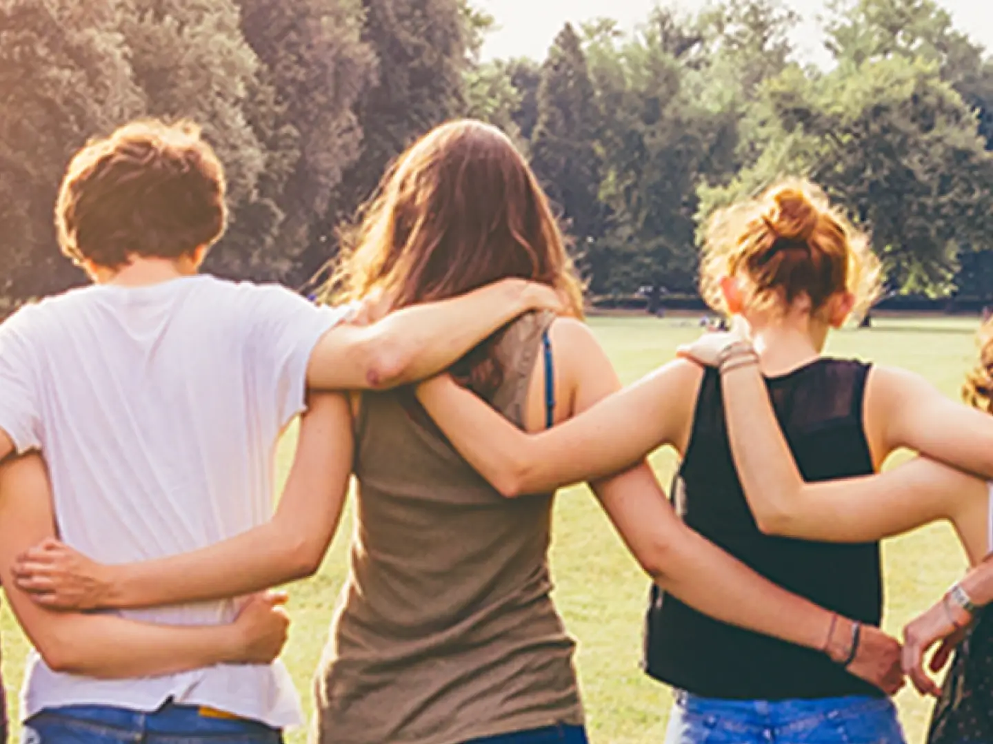\group of young adults standing in a park linking arms
